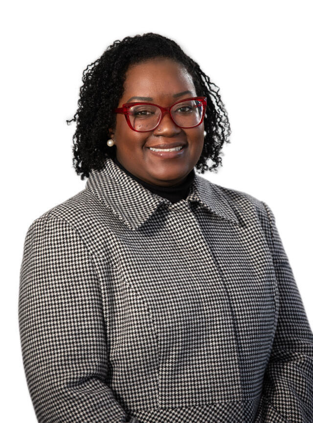 Professional photo of a smiling woman with short curly hair and red glasses.