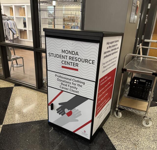 Black donation bin with white, gray, and scarlet graphics for professional clothing donations.